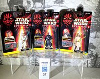 Front view of three factory-sealed Star Wars Episode I CommTech Chip figures on display stand
