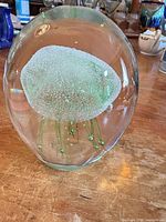 Front view of clear and green glass jellyfish paperweight