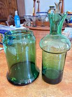 Both green glass vases side by side on tabletop