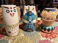 Front view of the three hand-painted ceramic vases/planters showing designs and rope/raffia accents