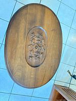 Oval table top showing carved floral medallion and scratches