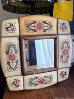 Front view showing square mirror, wood frame, floral faux leather panels