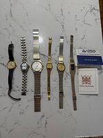 Six watches laid out side by side with Lorus box and booklet