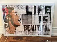 Framed Mr. Brainwash Billie Holiday poster on floor leaning against wall
