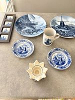 Group shot showing all items: two large plates, two small saucers, mug, four-tile coaster frame, candle holder