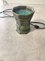 Front view of green ceramic wax warmer with melted wax and cord