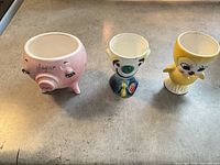 Front view of pig sugar bowl, clown egg cup, chick egg cup
