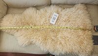 Full view of sheepskin rug with measuring tape indicating length