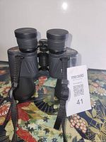 Rear view of binoculars with eyepieces, focus wheel, neck strap visible