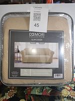 Front of packaged Demori Collection sofa slipcover showing label