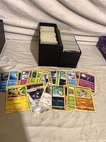 Overall lot view showing two storage boxes filled with Pokémon cards and a spread of assorted cards in front