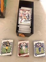 Open box filled with stacked 2024 Panini Absolute Football cards; three sorted piles and top card George Kittle visible