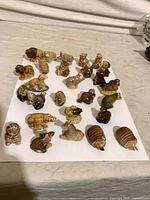 Full group shot of 27 glazed ceramic animal figurines on white background