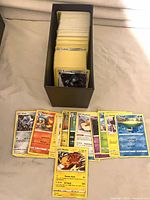 Full lot showing storage box filled with cards and sample spread of Pokémon cards