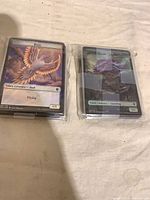 Two stacks of sleeved foil token cards, Bird and Saproling visible