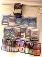 Stack and spread of assorted foil basic lands in sleeves