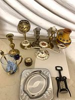 Group shot of all items showing variety of candlesticks, candelabra, glass mug, pitcher, ashtray and corkscrew