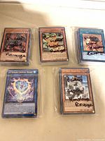 Four sealed team bags each containing a stack of Yu-Gi-Oh cards; top cards visible