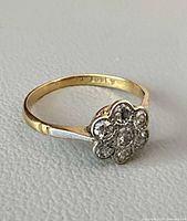 Ring angled view showing diamond cluster, yellow and white gold, hallmark inside band