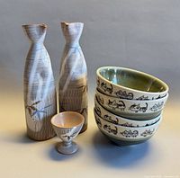 Full lot showing two sake bottles, one footed cup, four cat motif rice bowls stacked