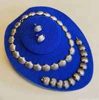 Necklace, bracelet and earrings displayed on blue felt