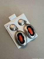 Front view of both earrings showing coral cabochons and silver setting