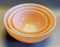Three peach lustre Fire-King bowls nested