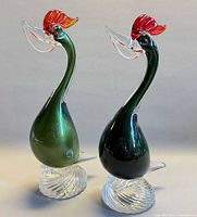 Front view of both glass pelican figurines showing overall form and color