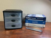 Plastic organizer, copy paper reams, clear tray on desk