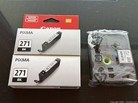 Two boxed Canon CLI-271 BK ink cartridges and one sealed Brother TZe-231 tape cartridge