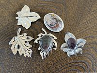 All five brooches arranged on wood surface