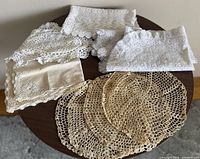 Group of assorted crocheted lace pieces on round table