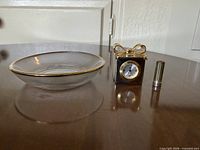 Glass dish, quartz clock, metal cylinder on table