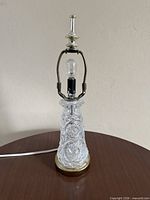 Full view of lamp showing glass body, metal base, harp and finial