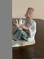 Front view of ceramic figurine showing elderly man with teapot