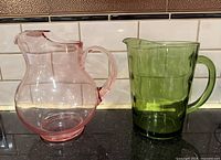 Pink and green glass pitchers side-by-side