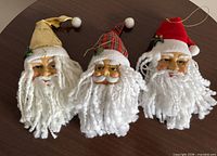 Front view of three Santa head ornaments on table