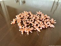 Pile of about 40 small plastic baby figurines on tabletop