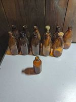 Ten loose brown glass bottles on table showing wear and residue