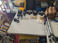 Table view showing both SLR cameras, five loose lenses, filters, manuals, bag and tripod