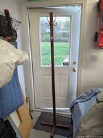 Full view of wooden coat rack with four hooks and cross base