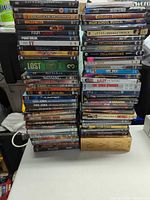 Two tall stacks of DVDs on table showing quantity and variety