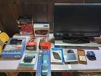 Overview of all electronics laid on table including monitor and boxed items