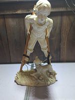 Front view of ivory resin figurine showing boy on stilts and dog on base