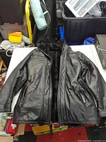 Front view of black leather coat with hood, faux fur lining visible