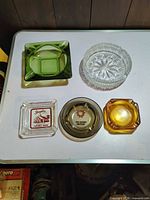 Group shot of five glass ashtrays in various colors and styles
