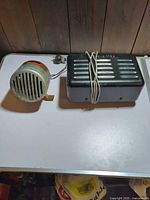 Precision Electronics siren and Bell System alarm bell side by side on table