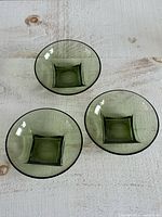 Top view of three matching green bowls showing square bases and round rims