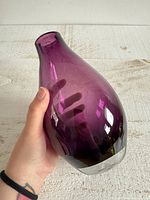 Full view of purple glass teardrop vase held in hand showing size and color gradient