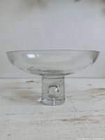 Side view of clear glass pedestal bowl showing overall shape and pedestal base with bubble.